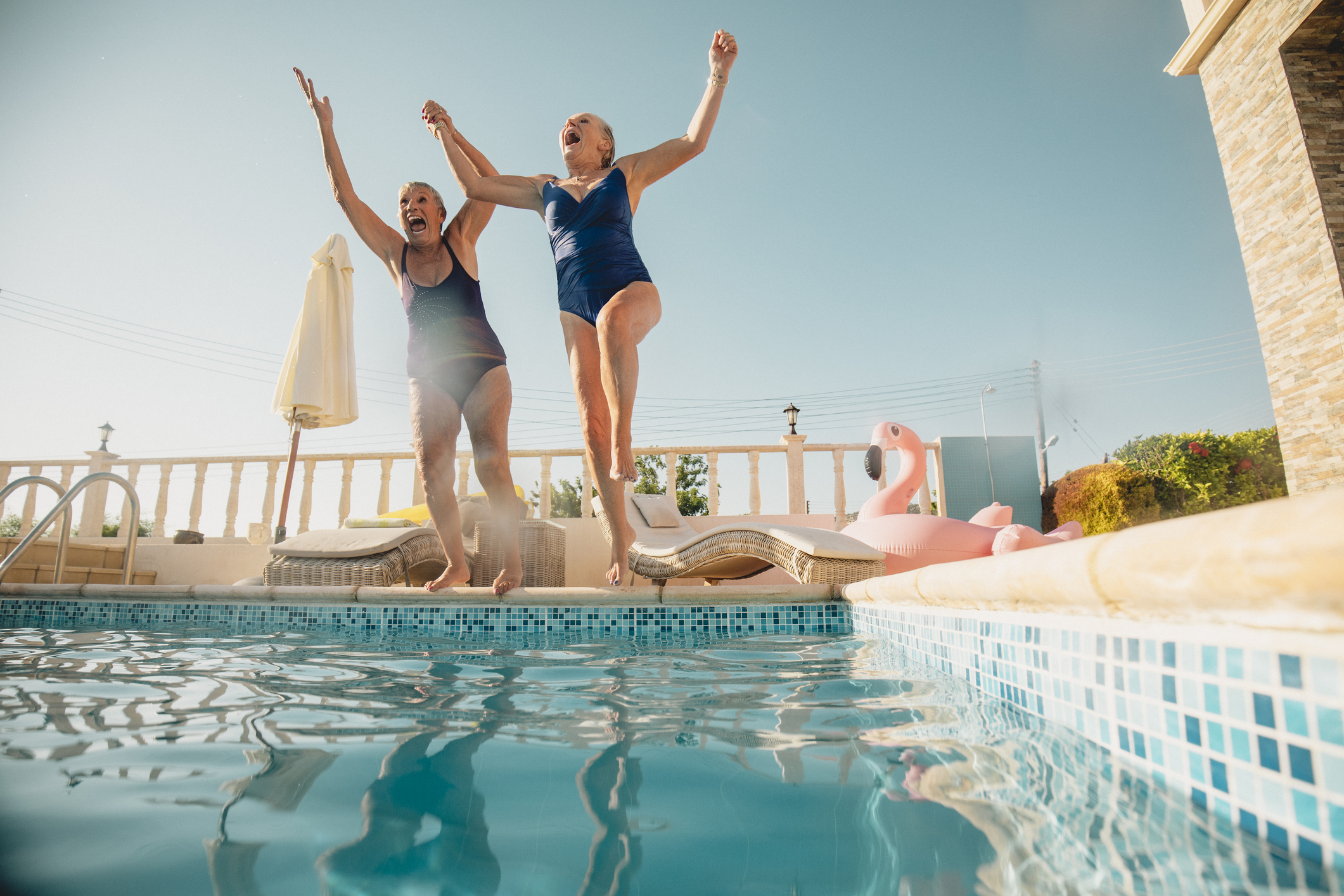 To ældre kvinder springer fra kanten ned i en pool