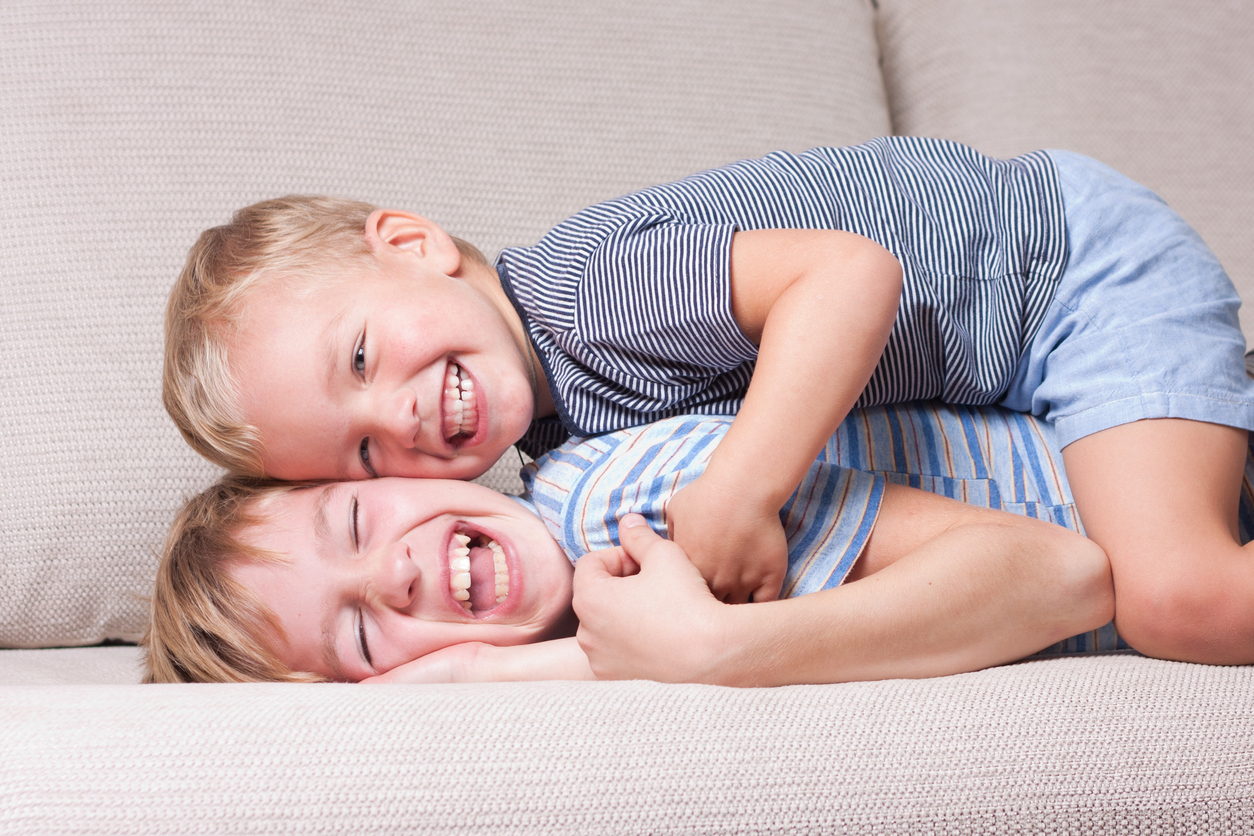 2 små drenge, der ligger og leger i en sofa
