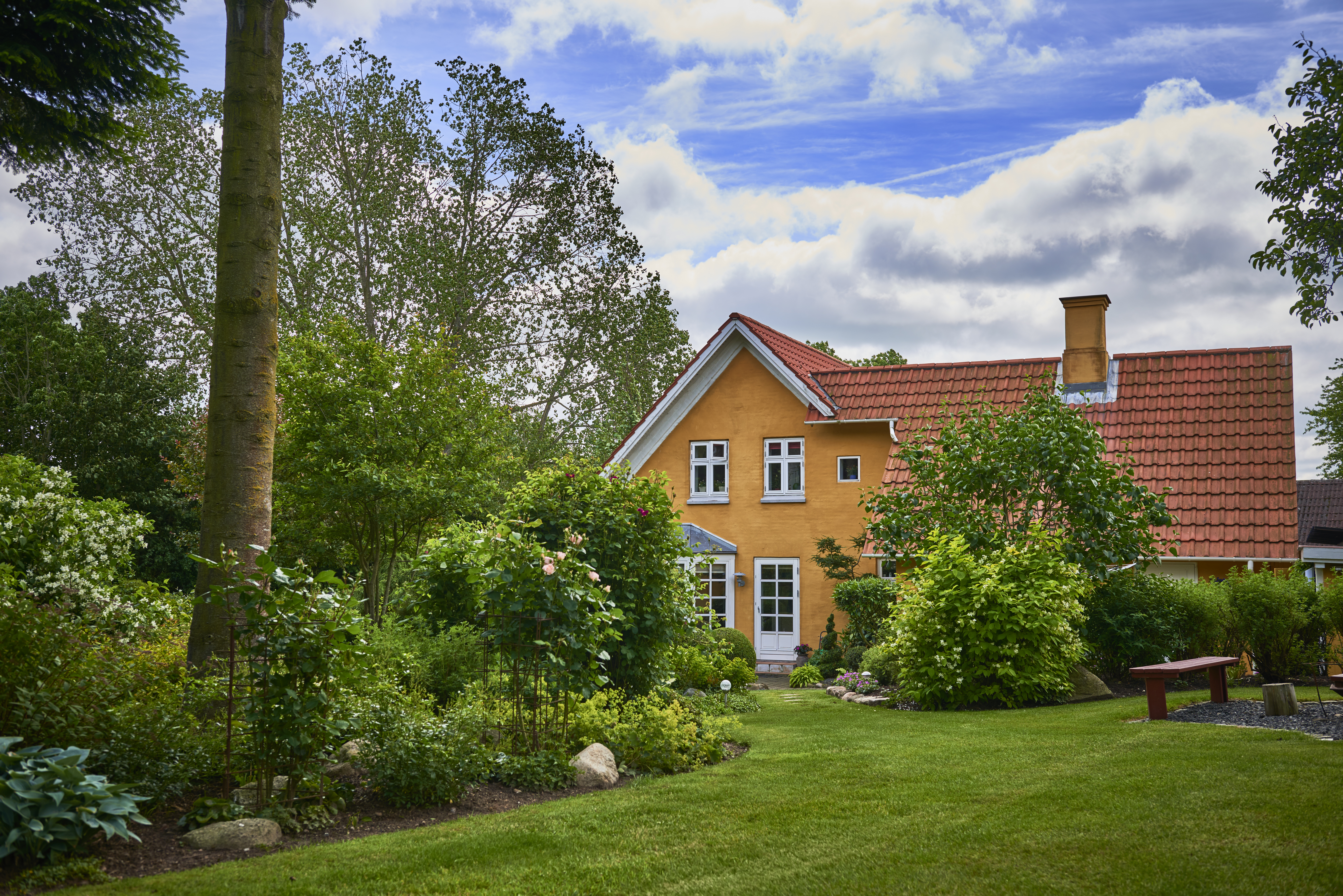 Gulmalet hus med stor frodig have.