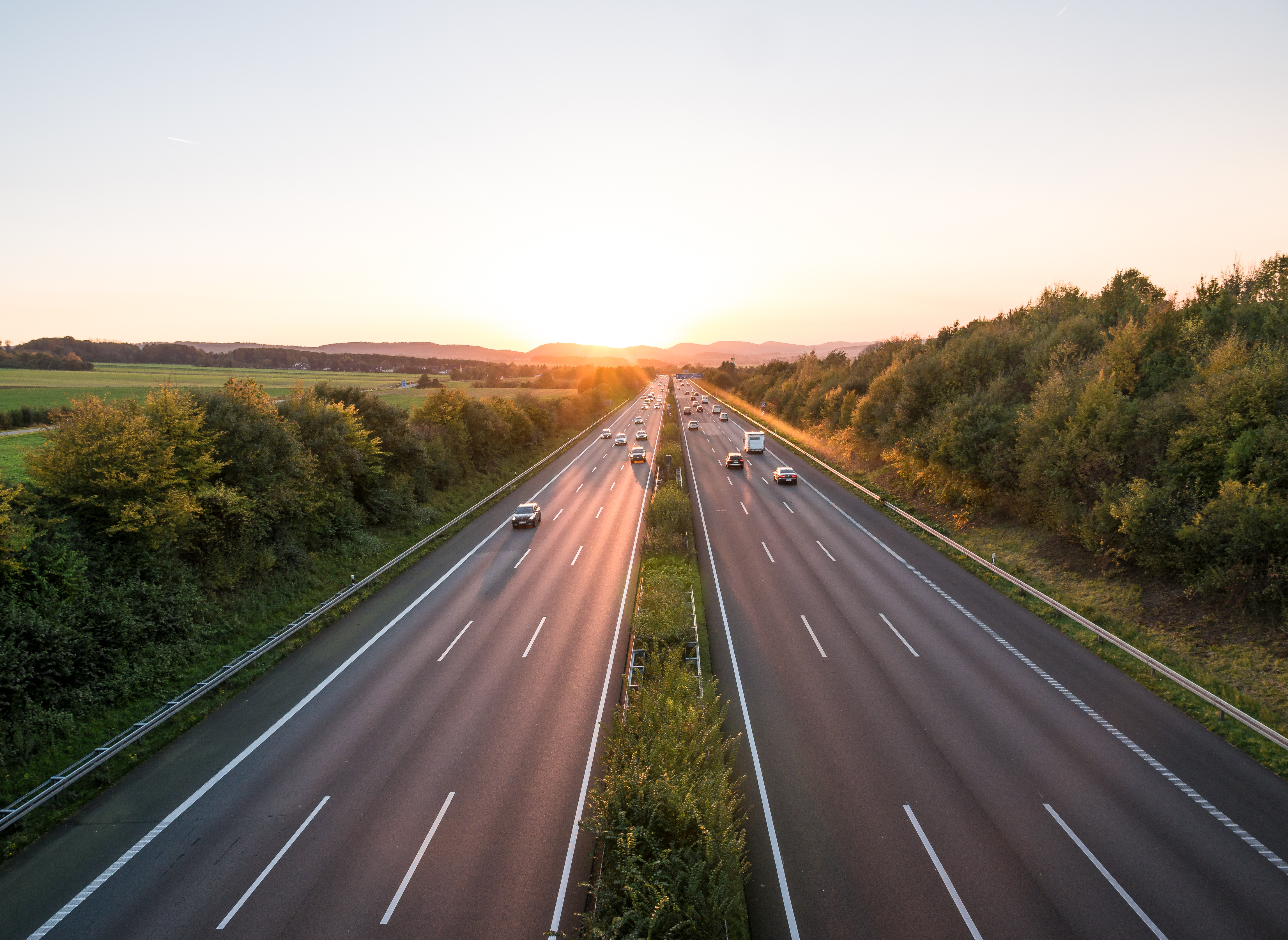En tresporet motorvej i morgensol, set oppefra