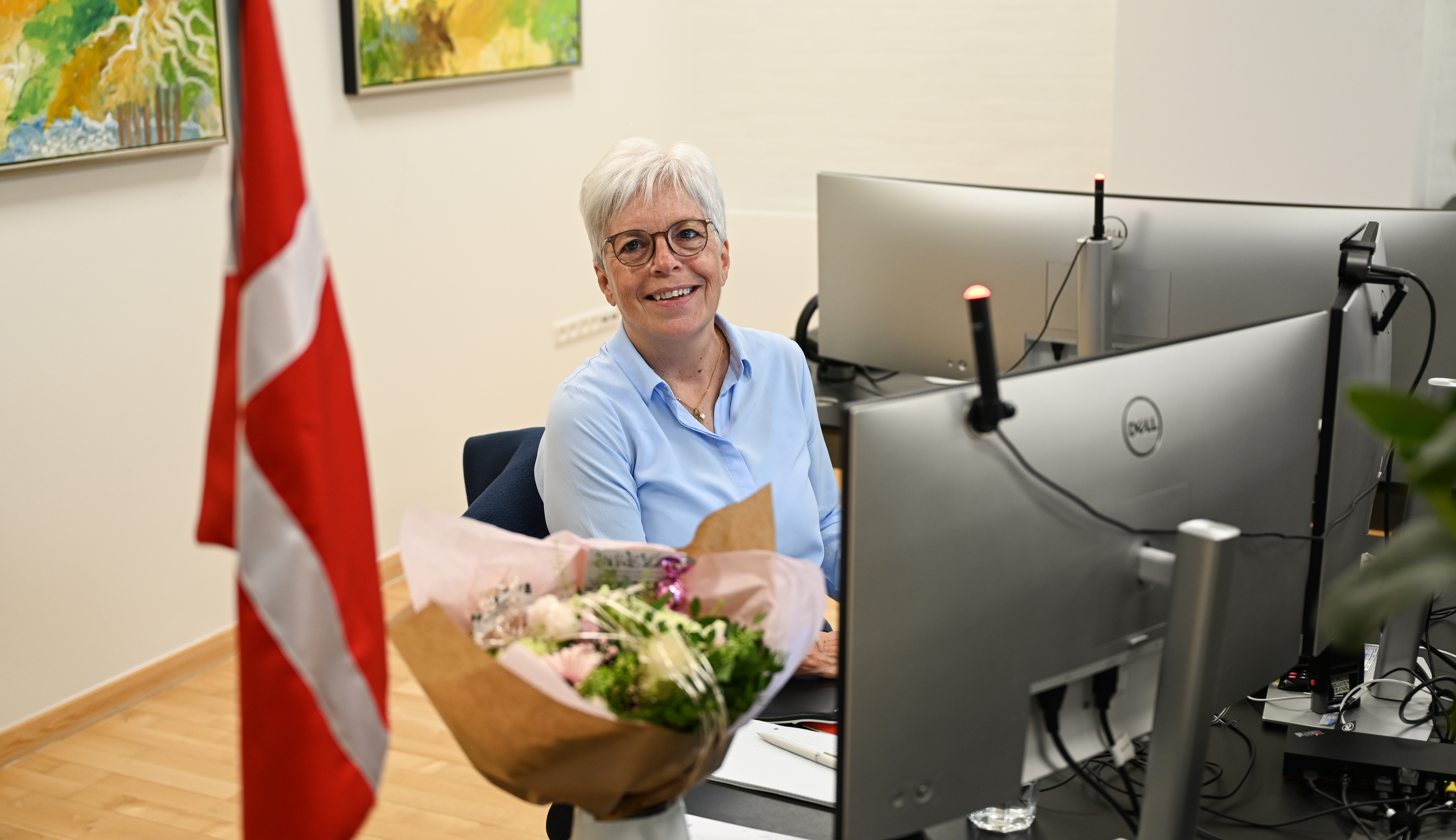 HM ved computeren med blomster og flag