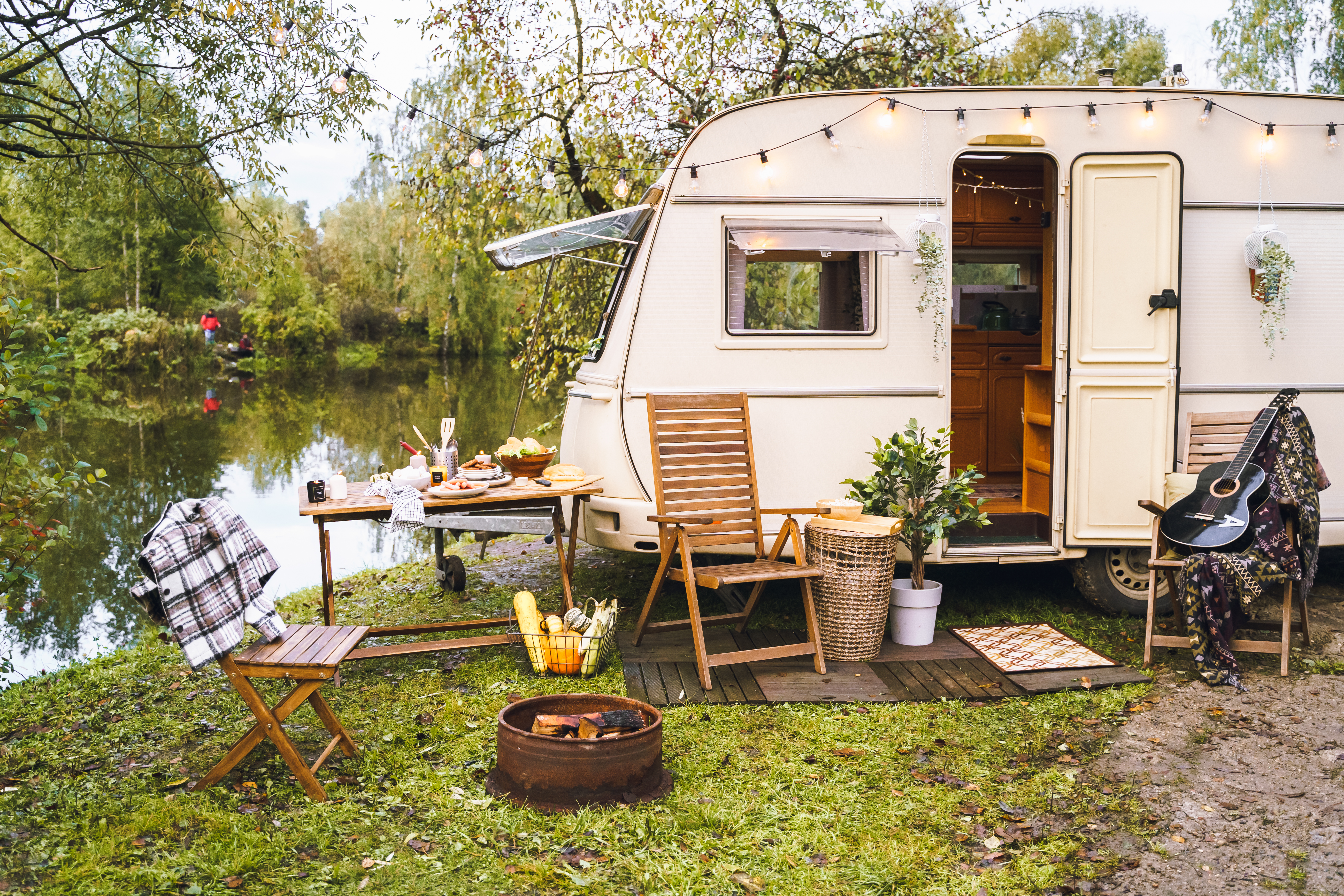 Campingvogn ved søbred med havestole og hygge