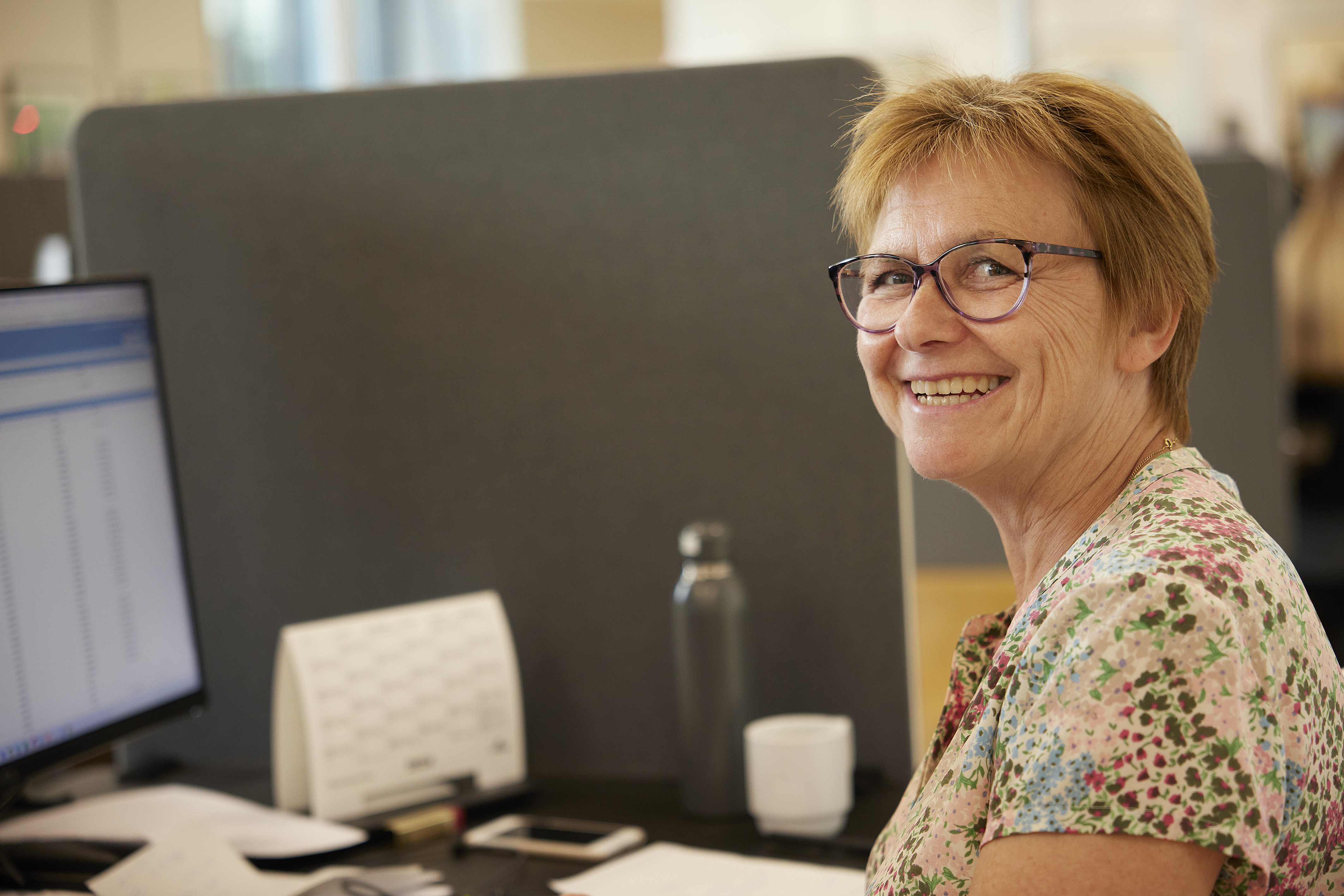 Smilende medarbejder ved sit skrivebord